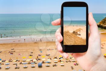 travel concept - tourist taking photo of Atlantic beach in Algarve, Portugal on mobile gadget