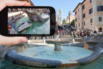 travel concept - tourist taking photo of Fountain of the Old Boat Spanish square with Spanish Steps on background, Rome on mobile gadget, Italy