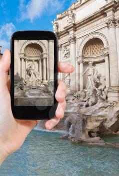 travel concept - tourist taking photo of sculptural composition of Trevi Fountain in Rome, Italy on mobile gadget