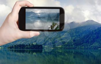 travel concept - tourist taking photo of Schliersee lake in Bavarian Alps on mobile gadget, Germany