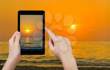 travel concept - tourist taking photo of yelow sunset in Black Sea in Crimea on mobile gadget