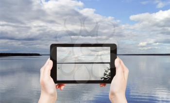 travel concept - tourist taking photo of Lake Seliger in Tver region on mobile gadget, Russia