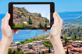 travel concept - tourist taking photo city Taormina from Castelmola, Sicily, Italy of on mobile gadget