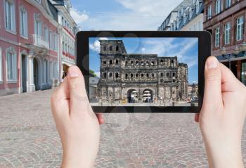travel concept - tourist taking photo of ancient roman Porta Nigra in Trier, Germany on mobile gadget