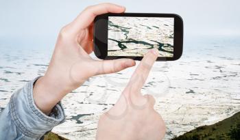 travel concept - tourist taking photo of ice blocks on coastline of Bering Sea on mobile gadget