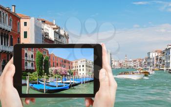 travel concept - tourist taking photo of parking of gondolas near Ponte di Rialto in Venice, Italy on mobile gadget