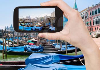 travel concept - tourist taking photo of gondolas near Piazza San Marco in Venice, Italy on mobile gadget