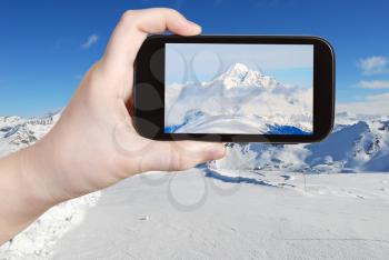travel concept - tourist taking photo of snow-covered mountain peak in Alpes, Val Gardena, Dolomites, Italy on mobile gadget