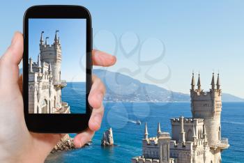 travel concept - tourist taking photo of Swallow's Nest palace on Southern Coast of Crimea on mobile gadget