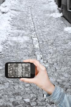 travel concept - tourist taking photo of cobblestone road in Zurich city in snow winter on mobile gadget, Switzerland