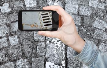 travel concept - tourist taking photo of wet cobblestone road in Zurich city after rain on mobile gadget, Switzerland