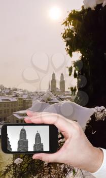 travel concept - tourist taking photo of Zurich city with towers of Grossmunster church in ewither evening on mobile gadget, Switzerland