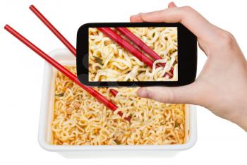 photographing food concept - tourist takes picture of red chopsticks on chinese cooked instant ramen on smartphone, Korea