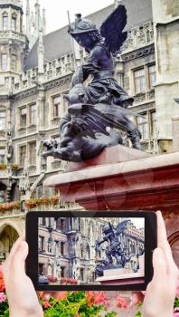 travel concept - tourist takes picture of sculpture on Mary's Column (Mariensaule) at marienplatz square in Munich on smartphone, Germany
