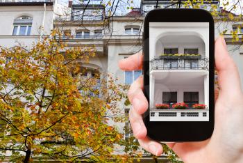 travel concept - tourist takes picture facade of urban mansion of the 19th century on Fasanenstrasse in Berlin in autumn on smartphone,