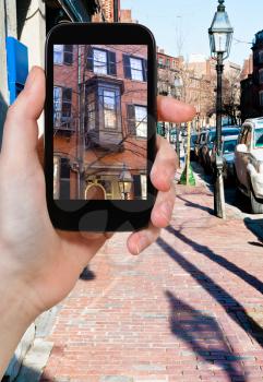 travel concept - tourist takes picture of Charles Street at Beacon Hill in Boston, USA on smartphone,