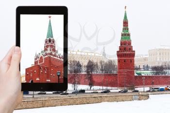 travel concept - tourist takes picture of snow in Moscow - view of Kremlin in winter snowing day on smartphone,