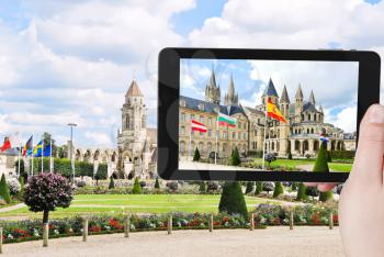 travel concept - tourist takes picture of medieval Church Saint-etienne-le-vieux on Place Monseigneur des Hameaux in Caen, France on smartphone,
