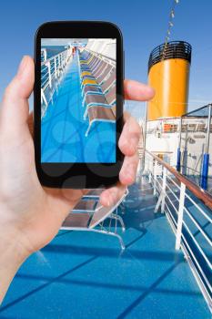 travel concept - tourist takes picture of sunbath chairs on upper deck of cruise liner on smartphone,