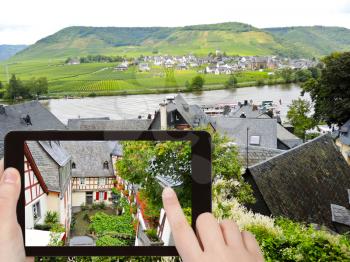 travel concept - tourist takes picture of traditional houses on narrow street in Beilstein village, Moselle region, Germany on smartphone,