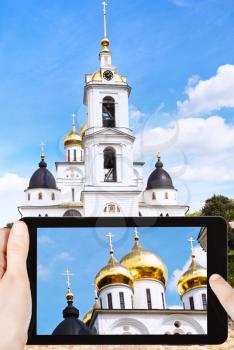 travel concept - tourist takes picture of Dormition Cathedral of Dmitrov Kremlin, Russia on smartphone,