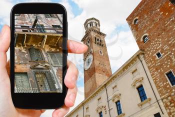 travel concept - tourist takes picture of shabby facade of old house in center of Verona city, Italy on smartphone,