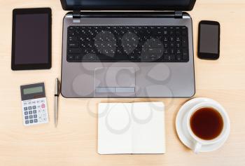 business still life - top view of laptop, tablet PC, smartphone, calculator, cup of tea, pen and notebook on office table