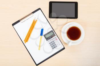 business still life - above view of tablet PC, clipboard, calculator, cup of tea, pen and pencil on office table