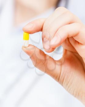 nurse holds pilule in fingers close up