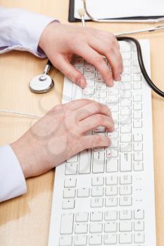 doctor works on white PC keyboard close up