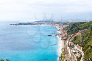 above view of Ionian Sea coastline and Giardini Naxos town from Taormina city, Sicily, Italy in spring