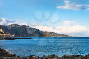 view of Giardini Naxos town, Taormina cape and rainbow in Ionian Sea in spring, Sicily
