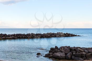 stones breakwater near beach of Giardini Naxos resort in Ionian Sea, Sicily
