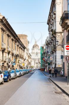 CATANIA, ITALY - APRIL 5, 2015: people on via Giuseppe Garibaldi and dome of Saint Agatha Cathedral in Catania, Sicily, Italy. Cathedral was originally constructed in 1078-1093.