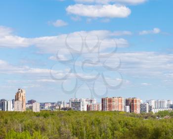 blue sky with white clouds over city and green forest in sunny spring day