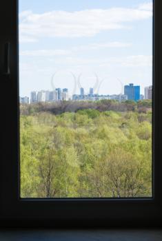 view of city and green woods from home window in spring day