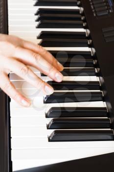 musician playing music on black and white keys of piano close up