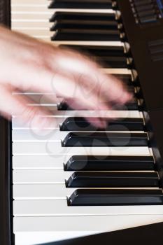 musician playing music on black and white keys of musical keyboard close up
