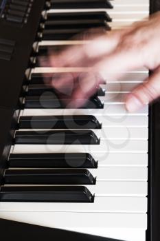 musician playing music on black and white keys of synthesizer close up