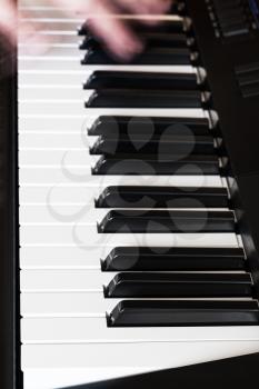 musician playing music on black and white keys of digital piano close up