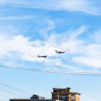 air refueling of turboprop bomber aircraft in blue sky over urban house