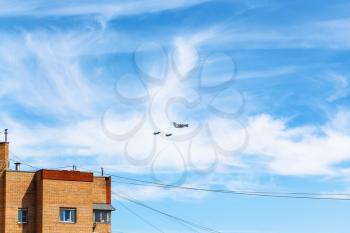 air refueling of military fighter aircraft in blue sky over urban house