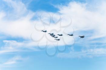 flight of military fighter aircrafts in white clouds in blue sky