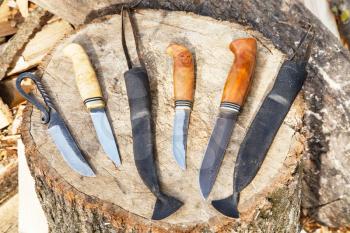 several hand made knives on tree stump