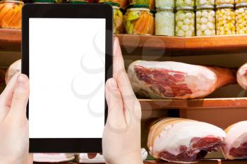 travel concept - tourist photograph hams and salty bacon in small local shop in Bologna, Italy on tablet pc with cut out screen with blank place for advertising logo