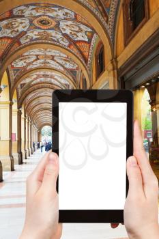 travel concept - tourist photograph medieval artistic portico on piazza Cavour in Bologna, Italy on tablet pc with cut out screen with blank place for advertising logo