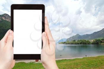 travel concept - tourist photograph Lake lago d idro from Idro town, Lombardy, Italy on tablet pc with cut out screen with blank place for advertising logo