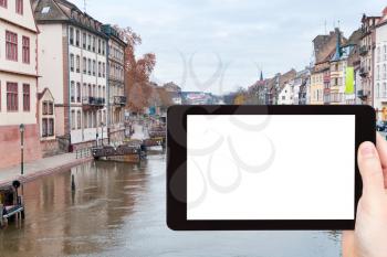 travel concept - tourist photograph bridge on Ill river canal in old Strasbourg town, France on tablet pc with cut out screen with blank place for advertising logo