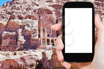 travel concept - tourist photograph Urn Tomb Cathedral in Petra, Jordan on smartphone with cut out screen with blank place for advertising logo