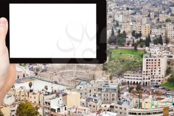 travel concept - tourist photograph ancient Roman theater in Amman city, Jordan on tablet pc with cut out screen with blank place for advertising logo
